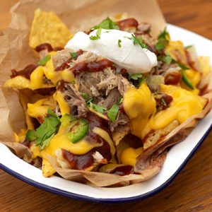 Corn tortilla chips topped with kalua pork, nacho cheese, sour cream, cabbage, jalapenos, BBQ sauce and cilantro.